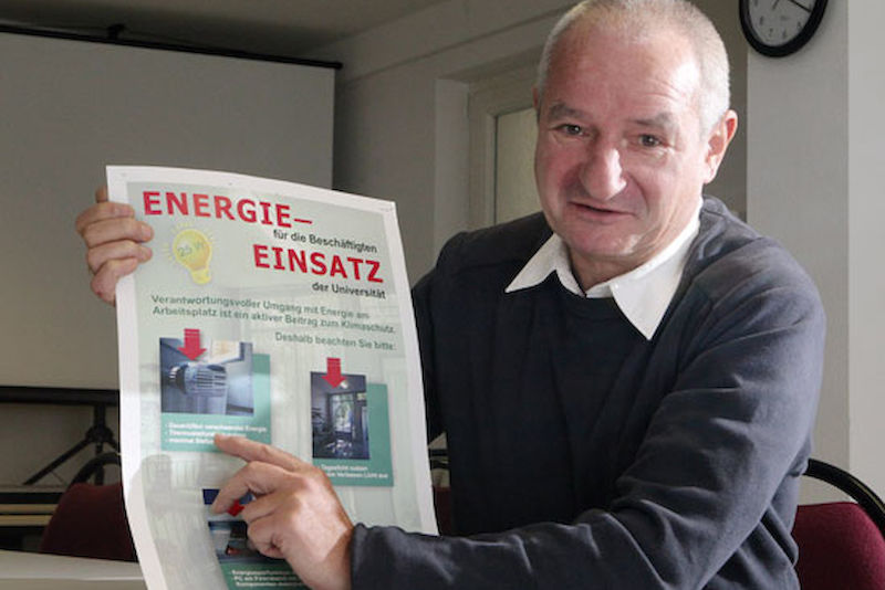 Techniker Klaus-Dieter Schubert mit einem Plakat, das die Uni-Techniker entworfen haben.