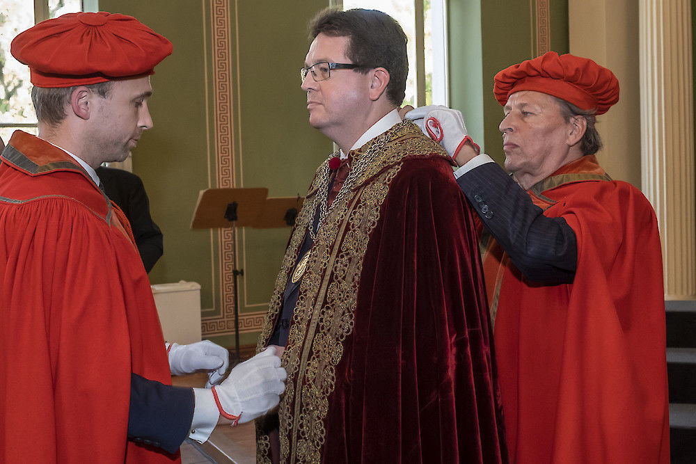 Kustos Michael Ruprecht (li.) und der ehemalige Kustos Ralf Speler übergeben Talar und Amtskette an Christian Tietje.