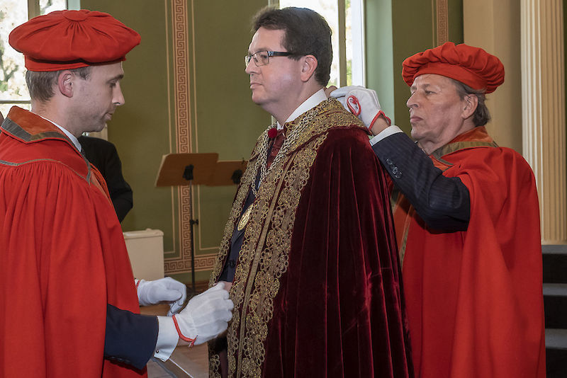 Kustos Michael Ruprecht (li.) und der ehemalige Kustos Ralf Speler übergeben Talar und Amtskette an Christian Tietje.