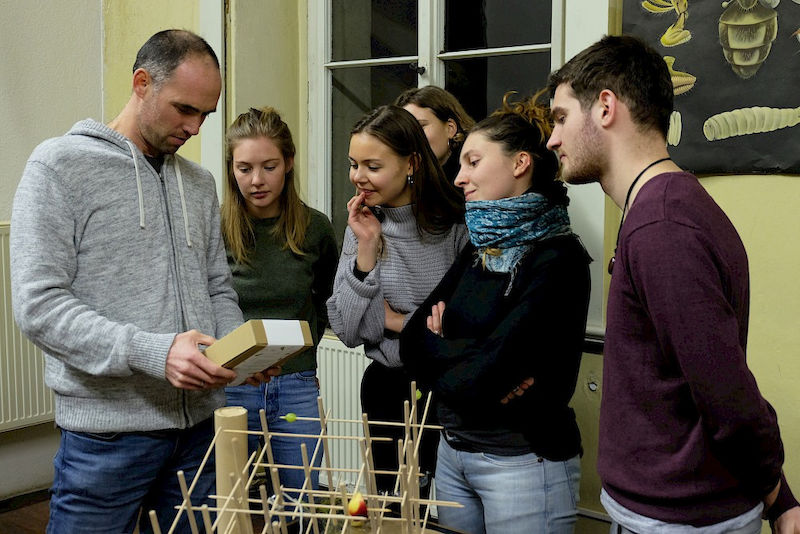 Gemeinsam mit den Studierenden betrachtet Frank Steinheimer ein Bau-Set, mit dem Futterknödel selbstständig hergestellt werden können und das durch Info-Karten gleichzeitig zur Beschäftigung mit den Tieren anregt.