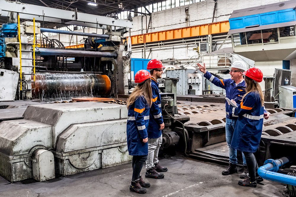 Ingenieur Olaf Schwedler erklärt Studierenden das riesige Walzwerk.