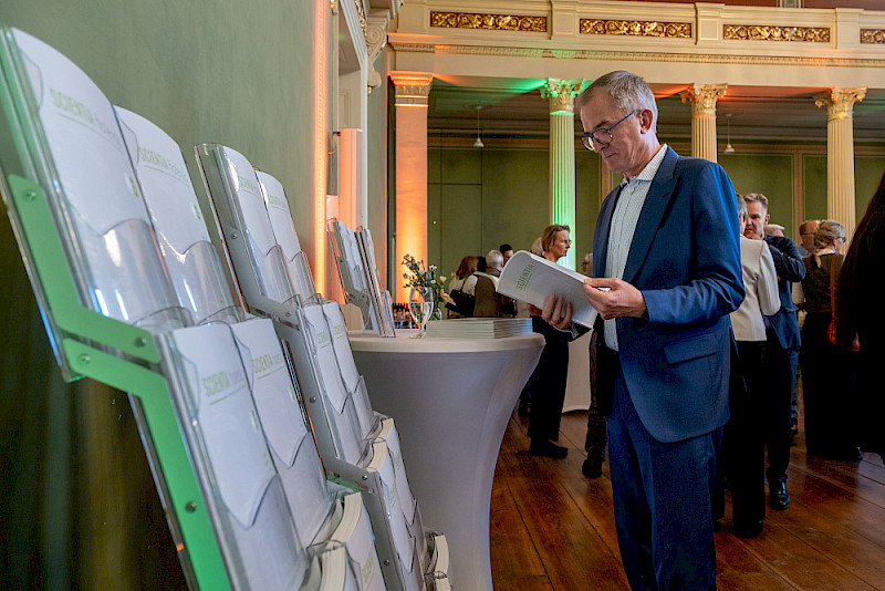 Der Landtagsabgeordnete Marco Tullner schaut in ein Exemplar des neuen Jahrbuchs „scientia halensis“.