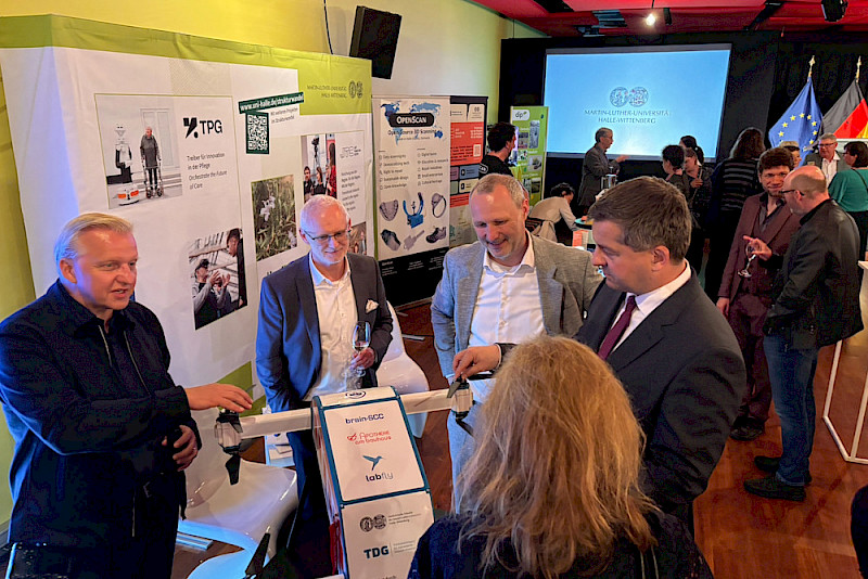 Ministerpräsident Sven Schulze (vorn rechts) am Stand der Universität im Gespräch über ein Projekt der TPG